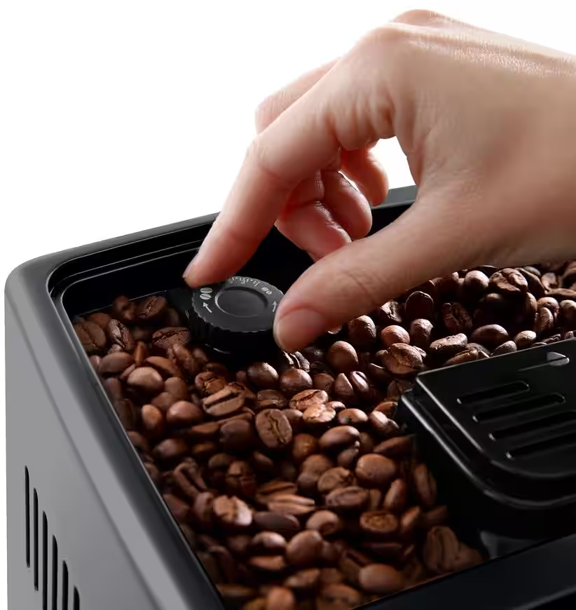 Una mano regola un quadrante su un contenitore di chicchi di caffè pieno di chicchi.
