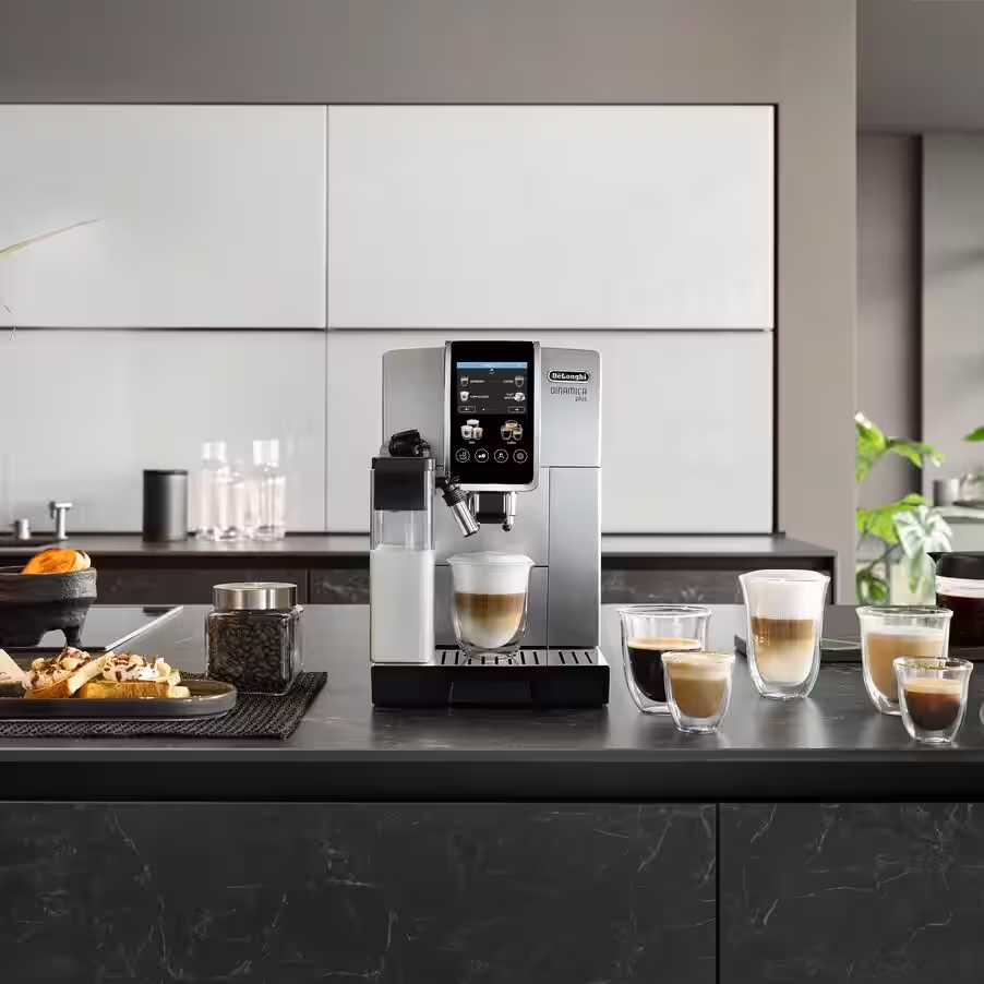 Macchina per espresso con tazze di caffè e chicchi di caffè su un bancone della cucina.