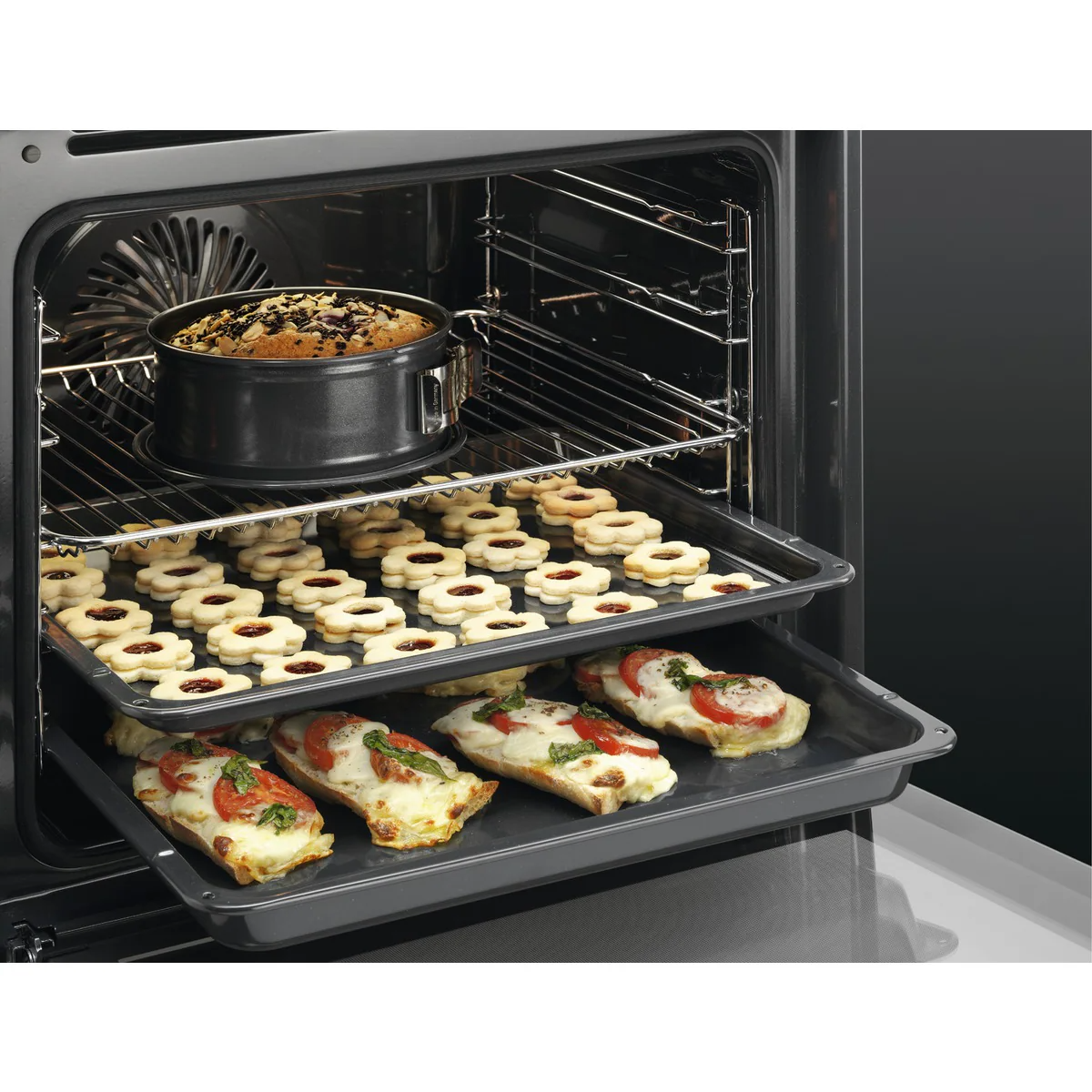 Horno con productos horneados. Un pastel, galletas y pizzas en diferentes rejillas.