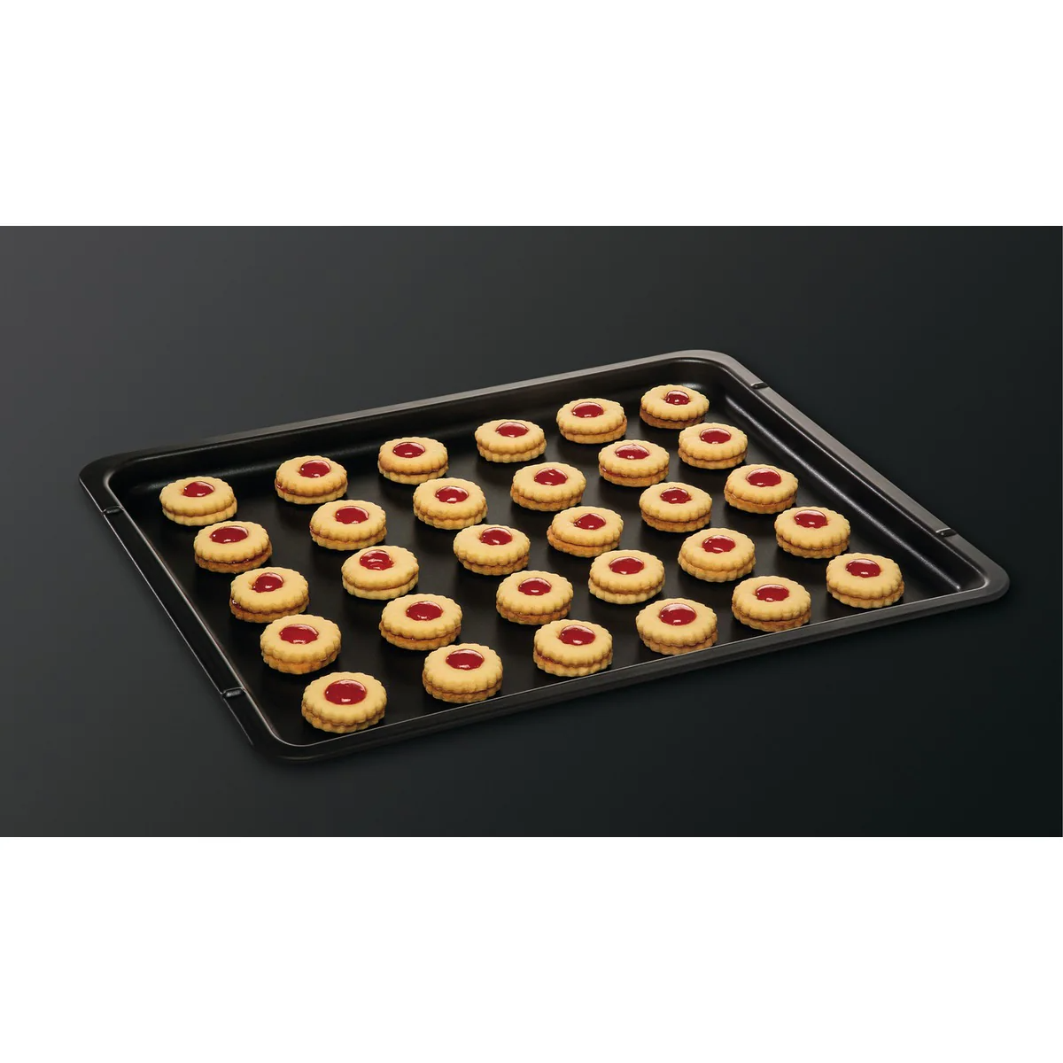 Una bandeja de galletas con relleno de mermelada roja sobre una superficie negra.