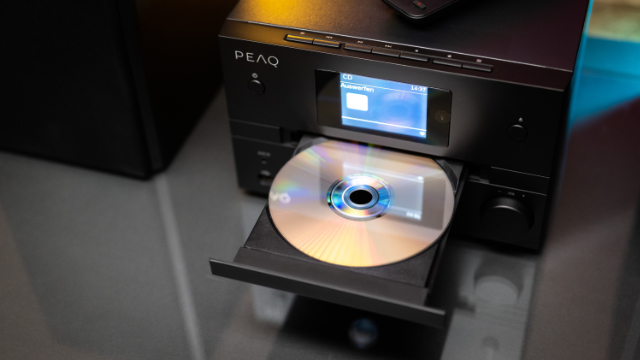 Fekete CD-lejátszó nyitott CD-tálcával. Egy CD a tálcában. A háttér elmosódott.