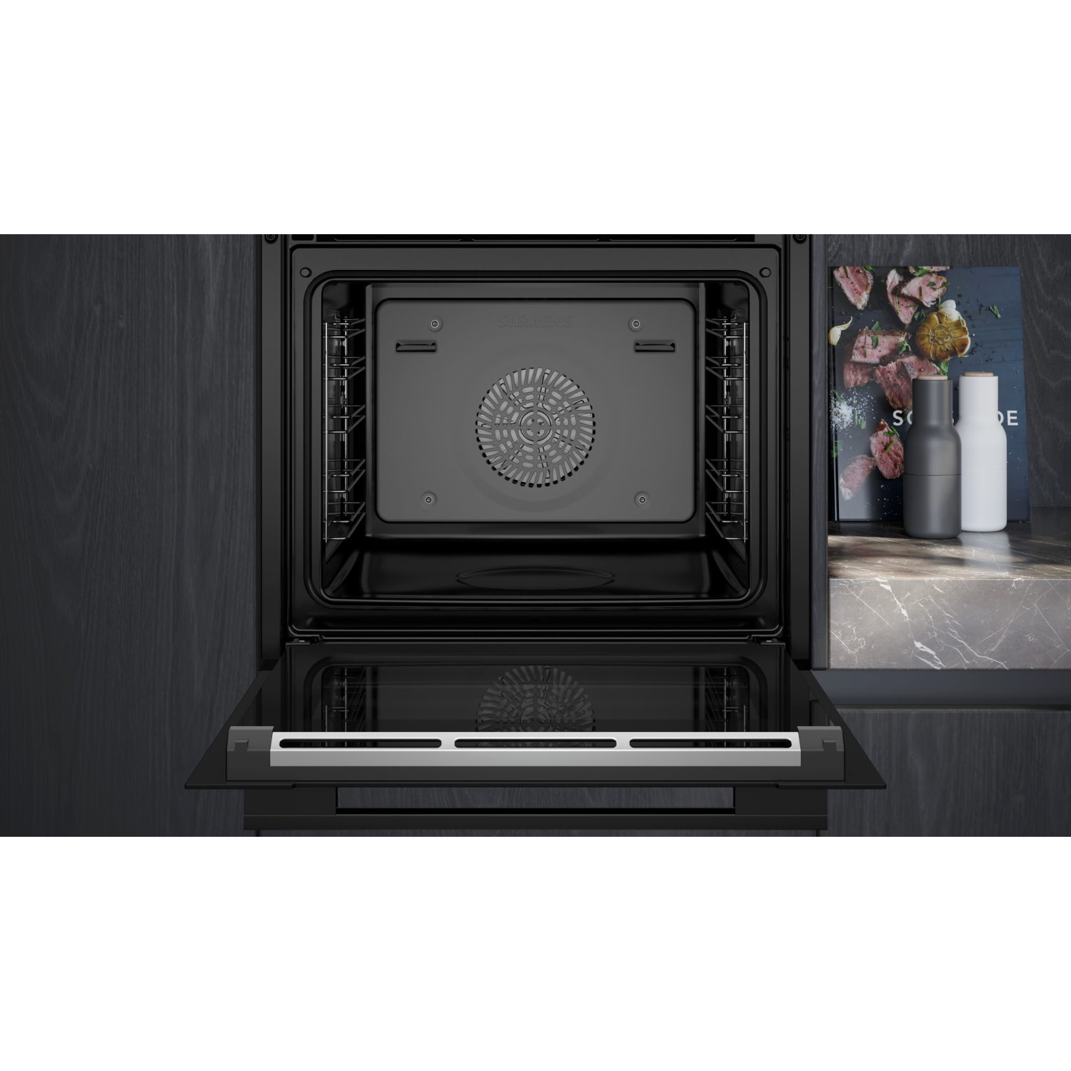 Open oven interior. Black interior with a fan and racks. The door is open, showing a silver handle.