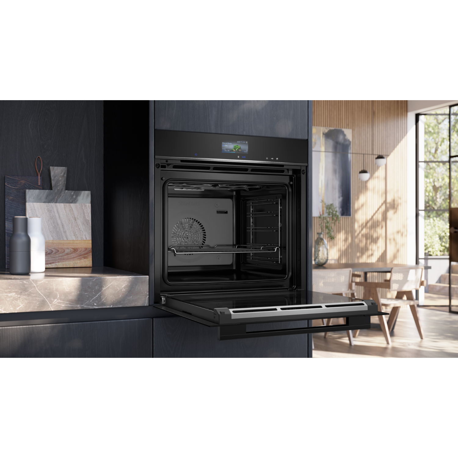 Built-in black oven with the door open. Inside, a rack is visible. Background features a kitchen and dining area.