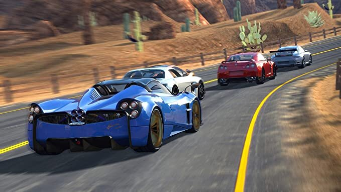 Trzy samochody sportowe ścigają się na autostradzie. W tle góry i kaktusy.