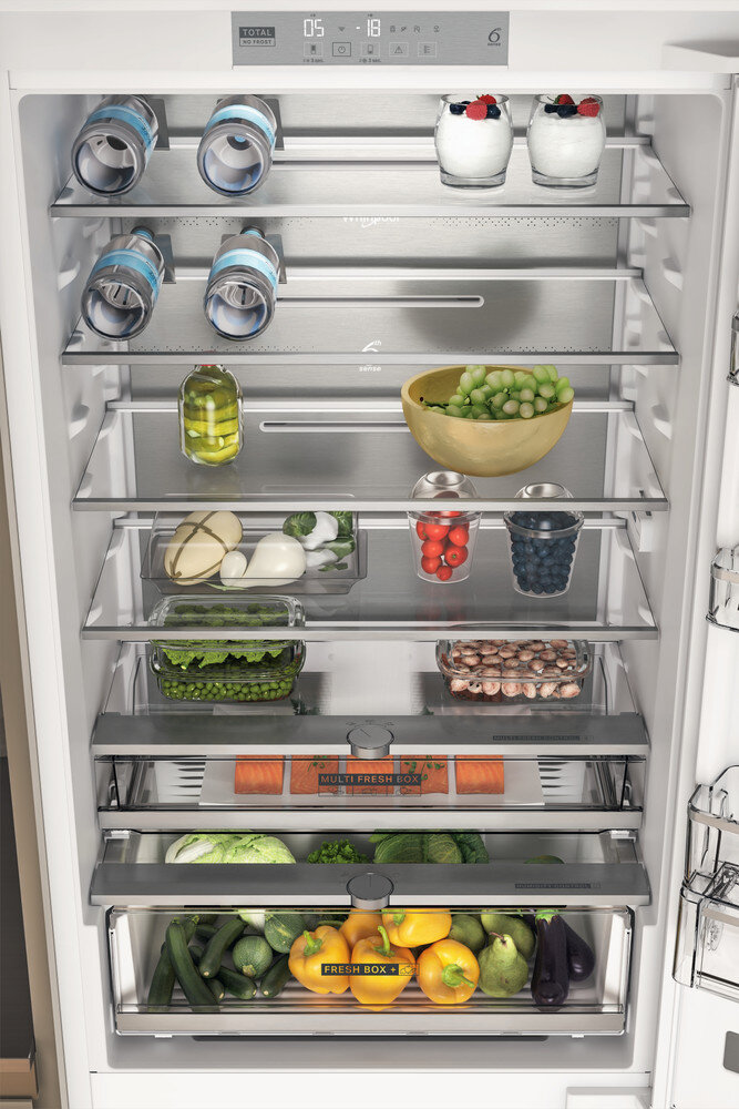 Otwarta lodówka z półkami jedzenia: butelki, jogurt, winogrona, pomidory, fasola itp.