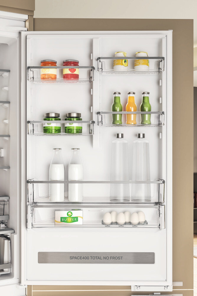 Wnętrze lodówki z półkami, na których znajdują się słoiki, butelki, jajka i masło.