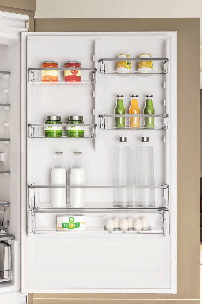 Wnętrze lodówki z półkami pełnymi produktów spożywczych, w tym słoików, butelek i jajek.