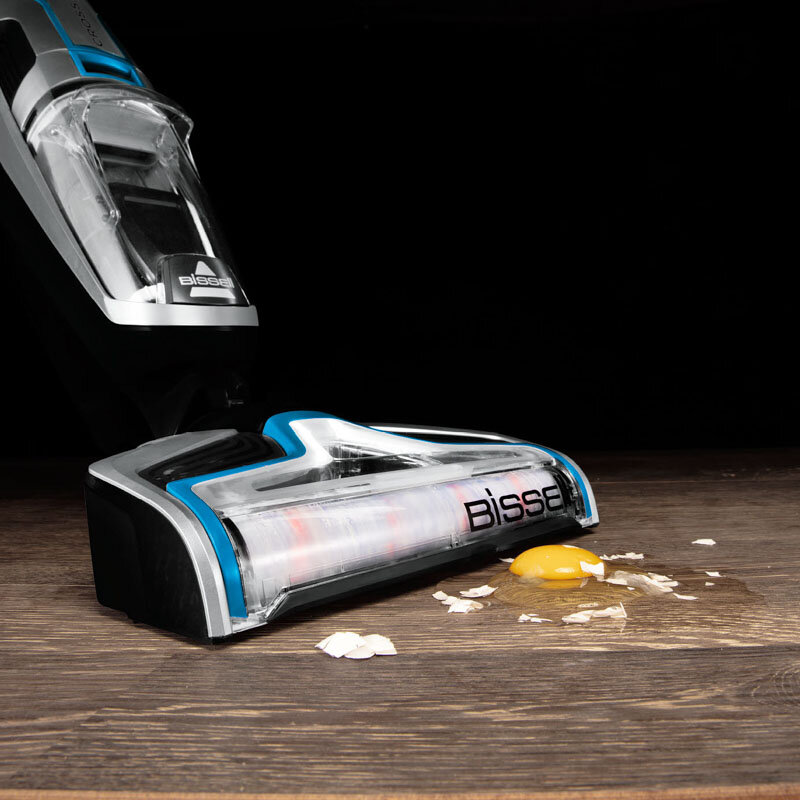 Głowica odkurzacza, rozbite jajko, na drewnie. Czarne tło.