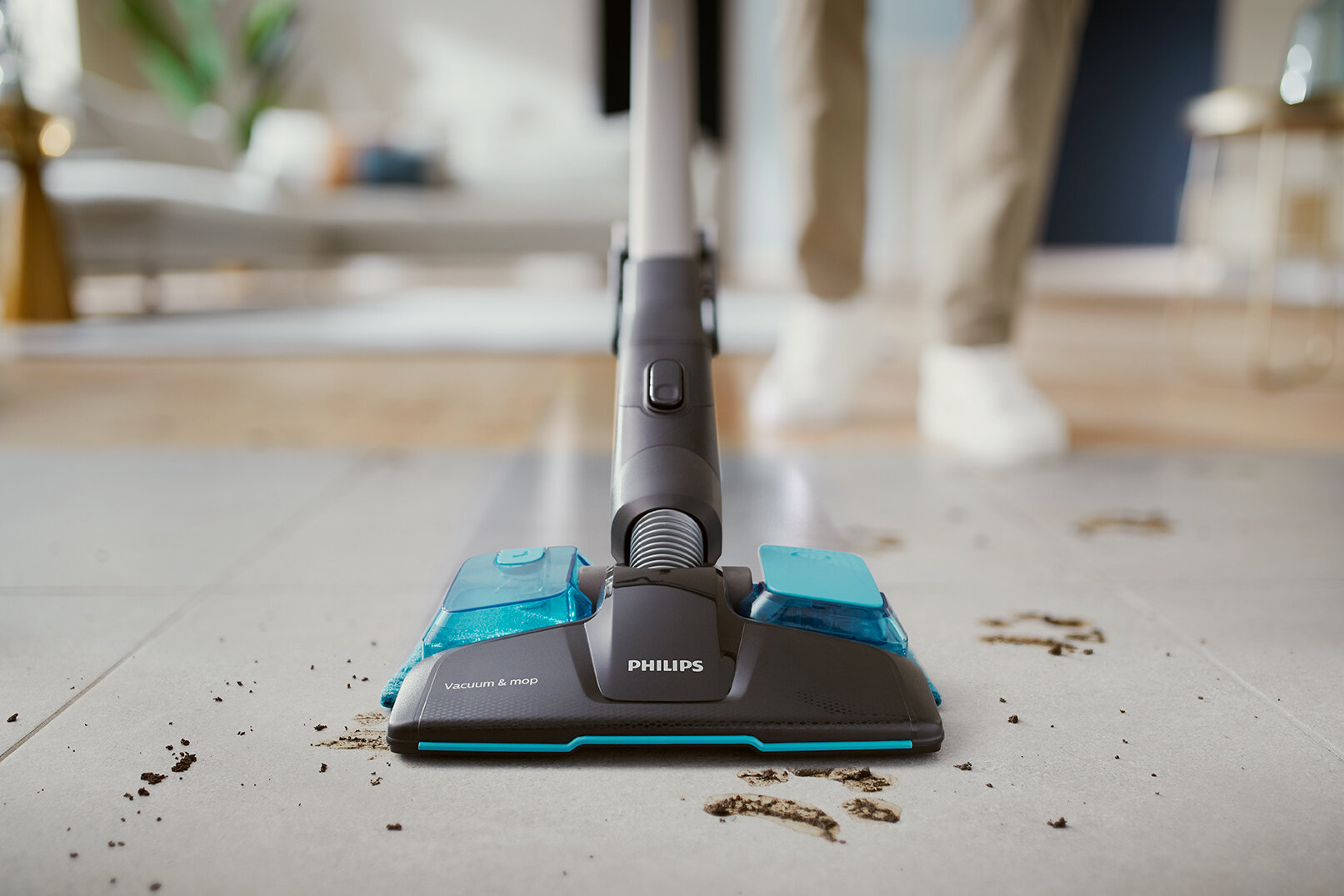 Odkurzacz i mop na podłodze z płytek z brudem i zanieczyszczeniami wokół niego.