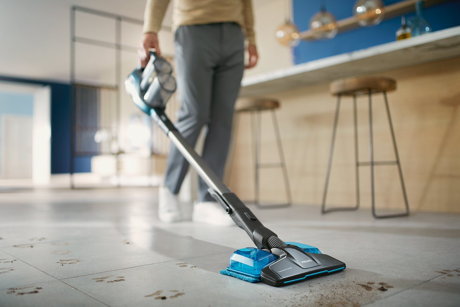 Osoba odkurza podłogę. Osoba używa bezprzewodowego odkurzacza z głowicą czyszczącą.