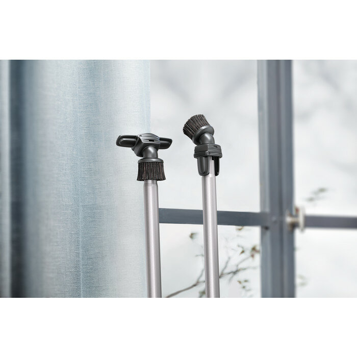 Dwie nasadki do odkurzacza ze szczotkami. Okno i zasłona w tle.