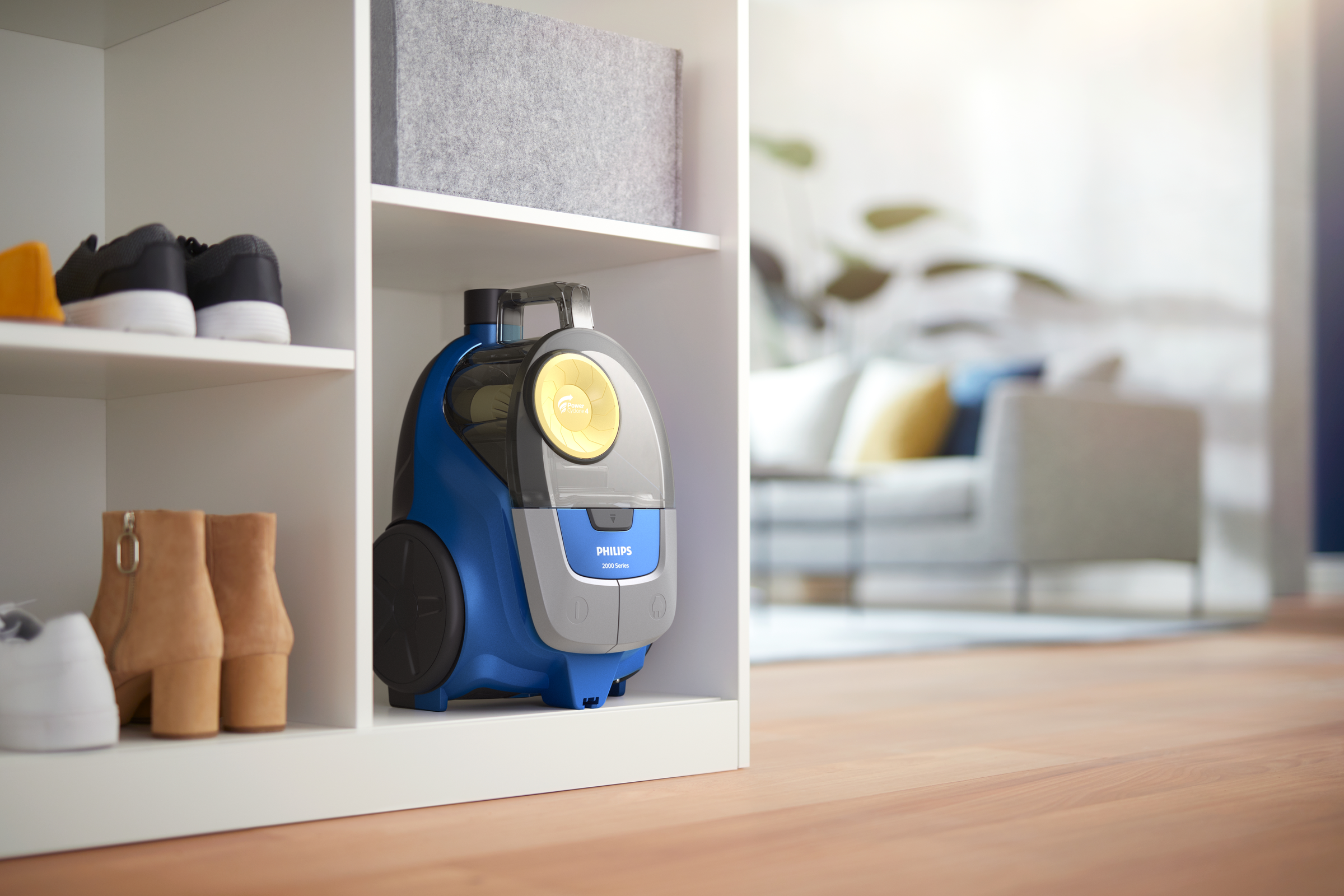 Niebieski odkurzacz w białej szafce obok butów i botków.
