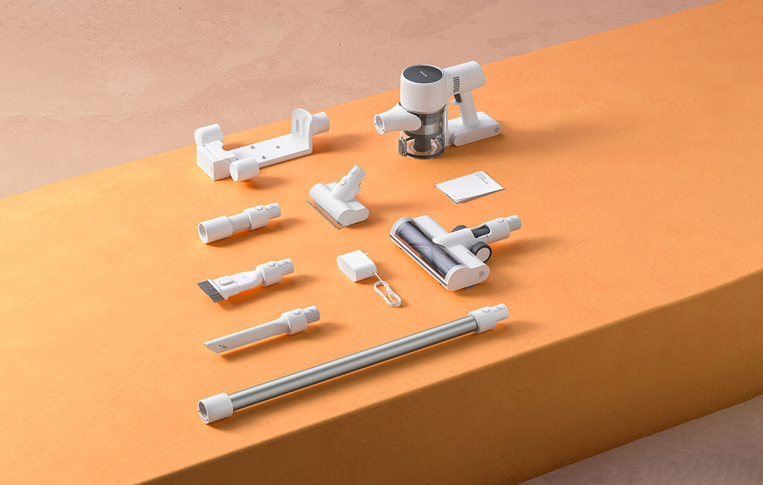 Akcesoria do odkurzacza na pomarańczowej powierzchni. Zawiera różne dysze i nasadki.