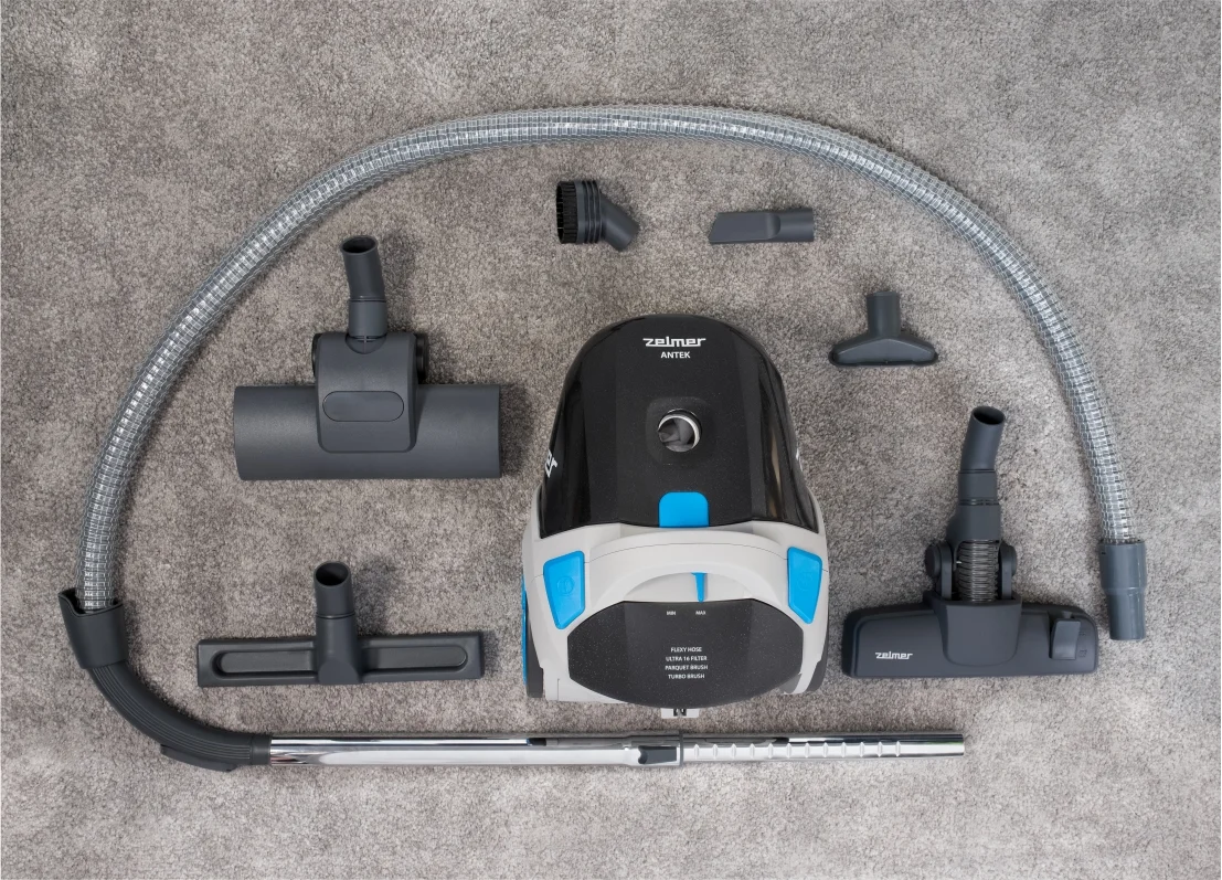 Odkurzacz i akcesoria starannie ułożone na szarym tle dywanu.