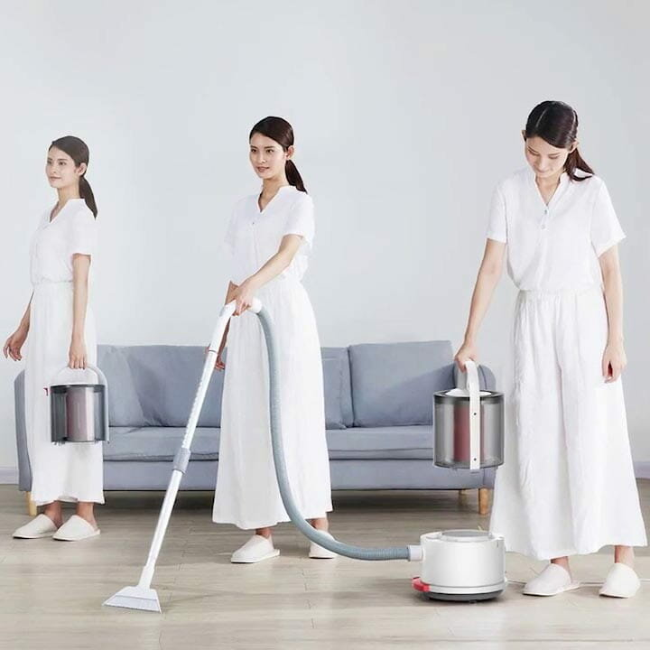 Kobieta odkurzająca pokój z białą kanapą.