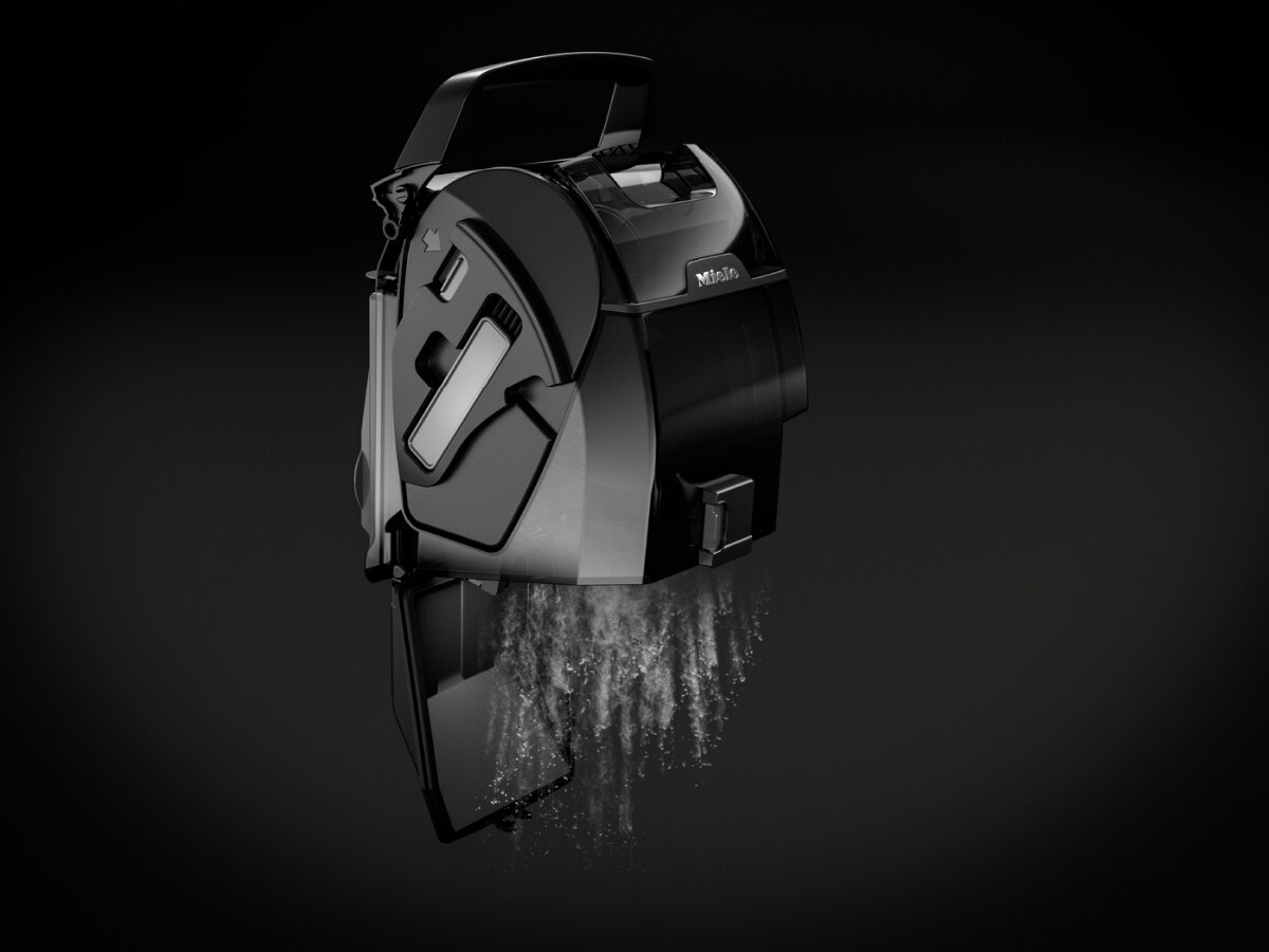 Czarny element odkurzacza z wodą. Woda wypływa, odsłaniając jego wewnętrzne części na czarnym tle.