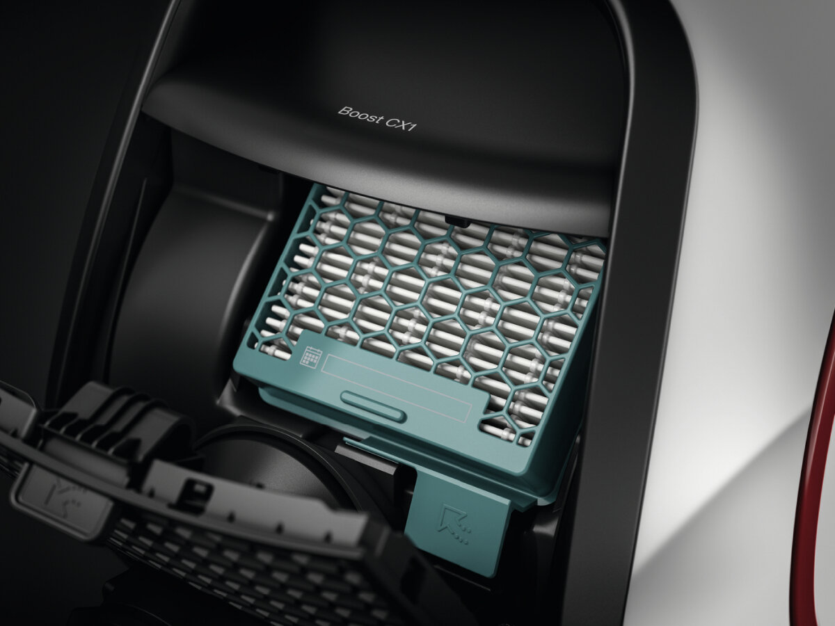 Zbliżenie na filtr odkurzacza. Filtr jest zielony i znajduje się w czarnej komorze.