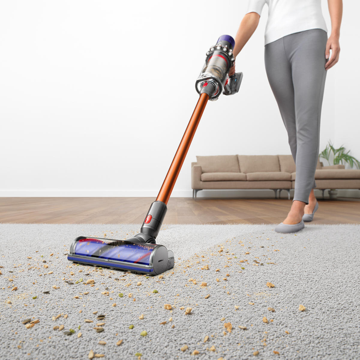 Osoba używająca odkurzacza na dywanie. Odkurzacz ma czerwono-szary design. Widoczne zanieczyszczenia.