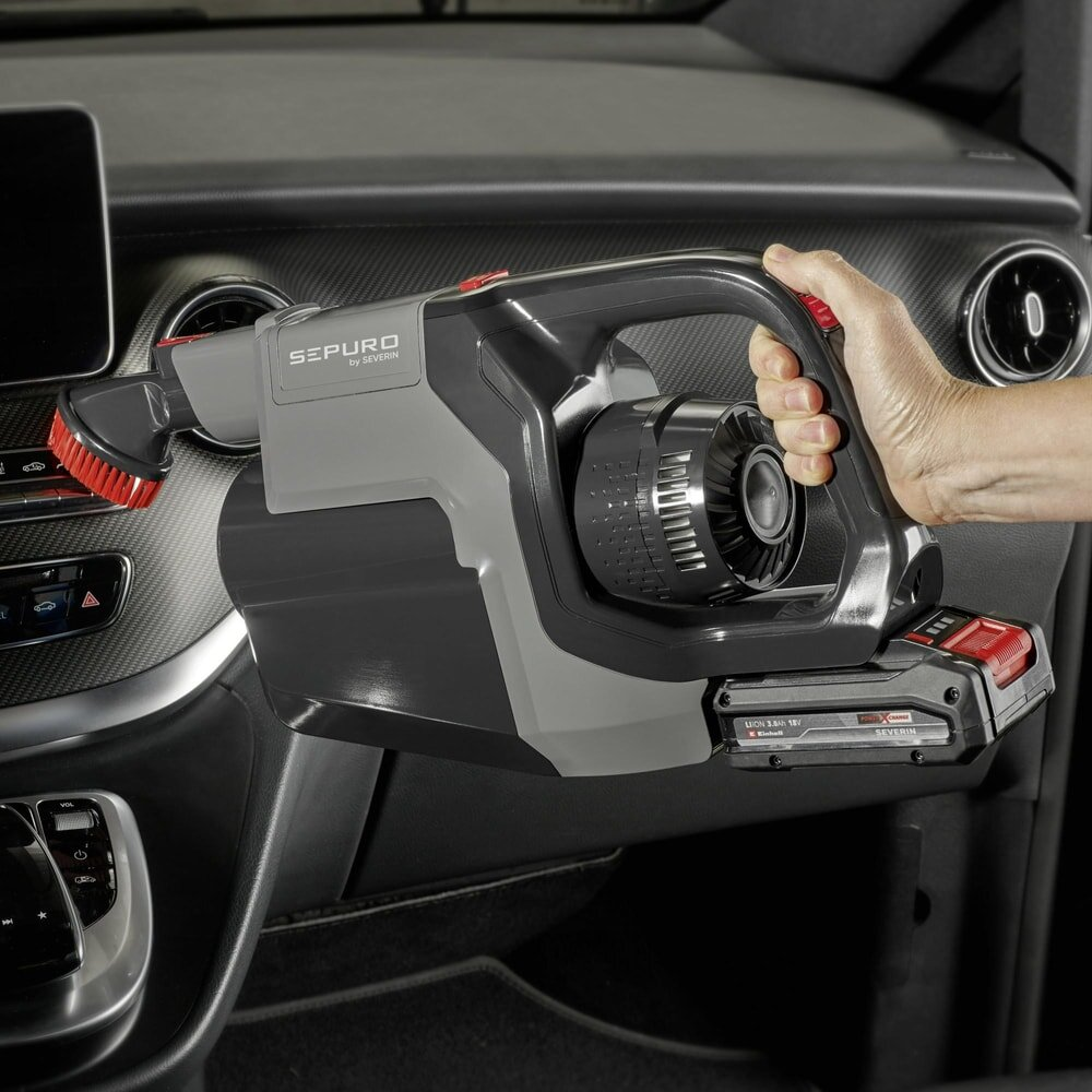 Odkurzacz ręczny używany w samochodzie. Odkurzacz jest szary i czarny.