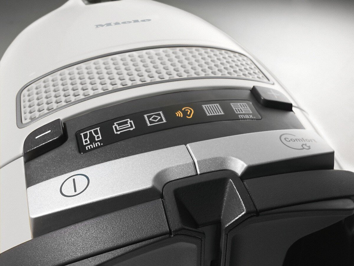 Zbliżenie panelu sterowania białego odkurzacza Miele. Widoczne są przyciski i kontrolki.