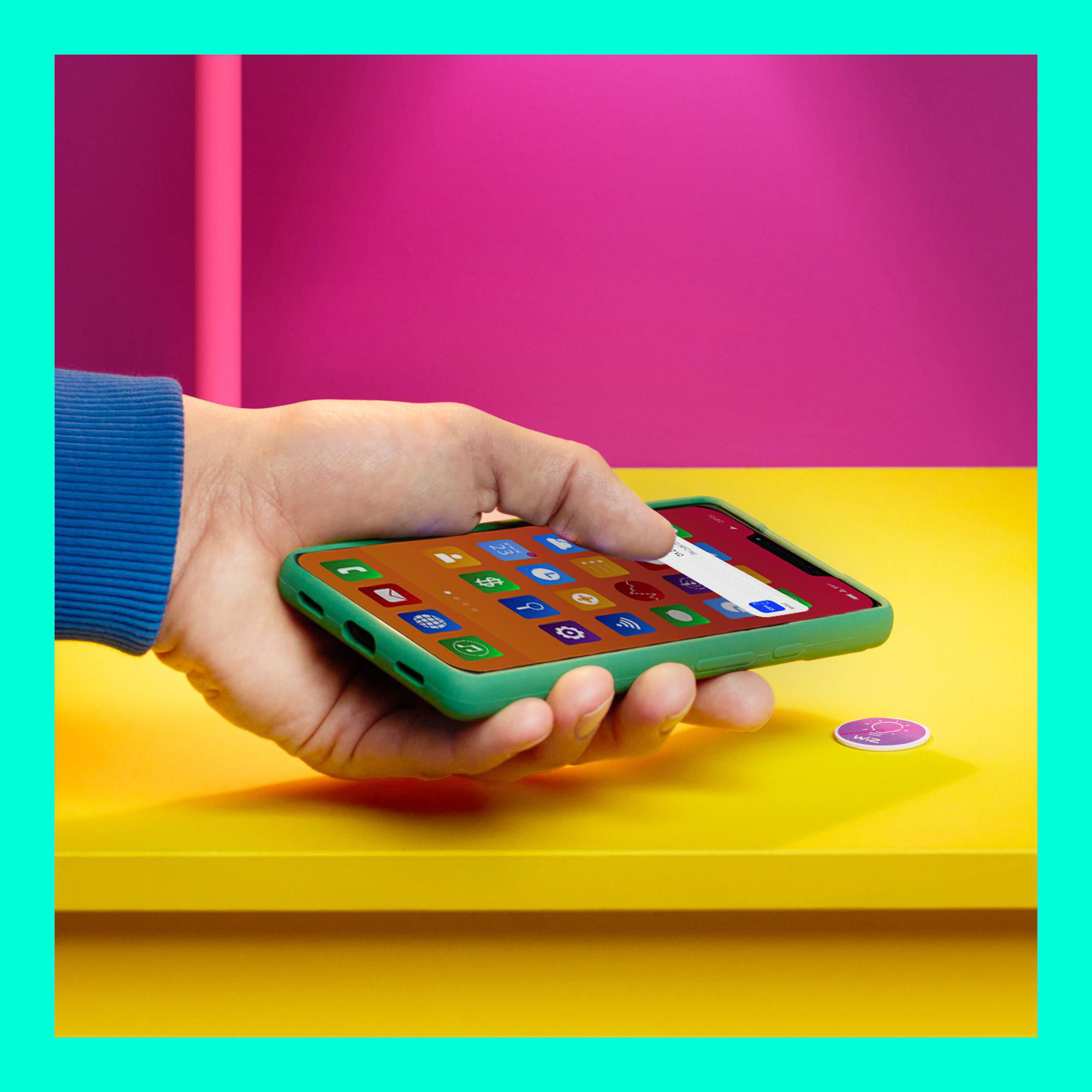 Eine Hand hält ein Telefon mit App-Symbolen. Das Telefon liegt auf einer gelben Oberfläche.