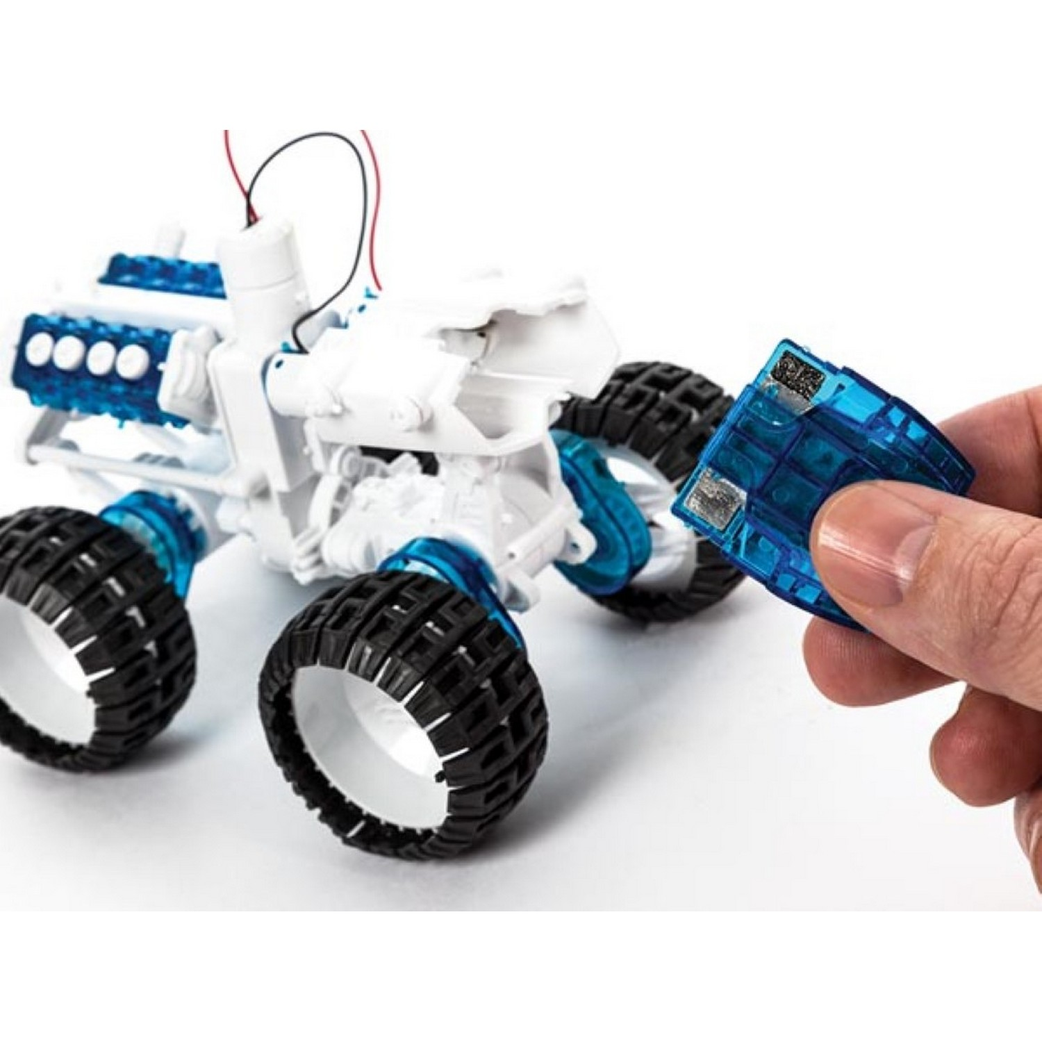 A person assembles a toy car with blue and white components.