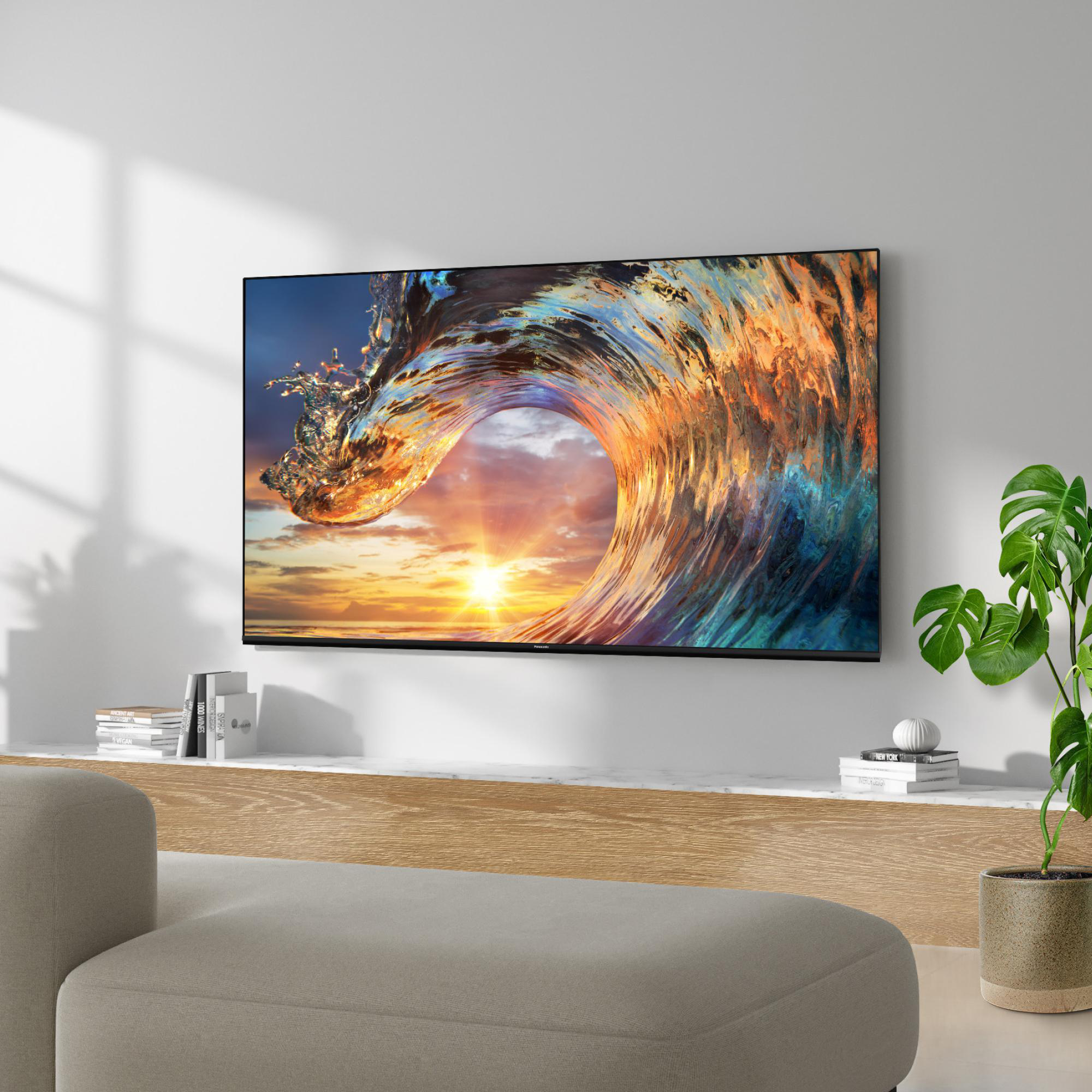 Ein großer Fernseher, der ein Wellenbild über einem Holzregal mit Büchern und einer Topfpflanze anzeigt.