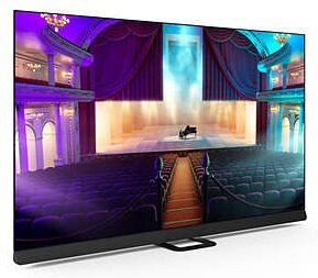 Duży ekran TV wyświetlający scenę teatralną. Wnętrze z miejscami siedzącymi.