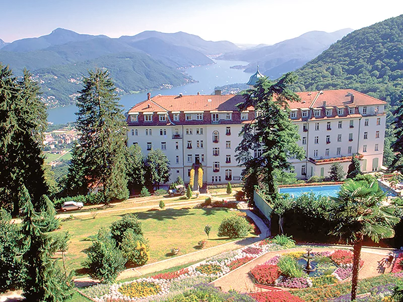 Hôtel et paysage avec lac et montagnes.