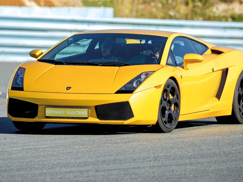 Un'auto sportiva Lamborghini gialla che guida su una pista. Due persone sono in macchina.