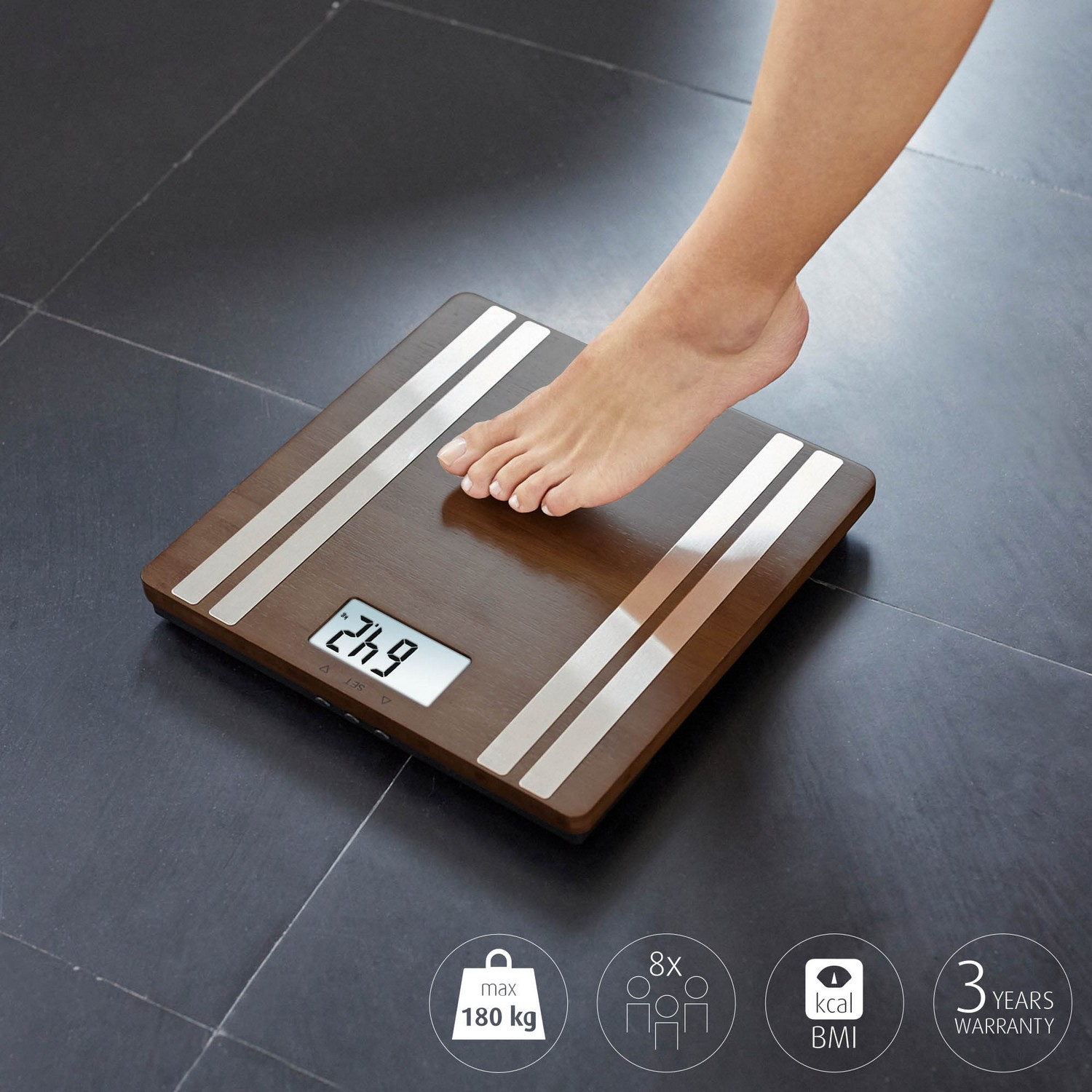 De voet van een persoon op een digitale weegschaal met een houten bovenkant. De weegschaal geeft het gewicht in kilogram aan.