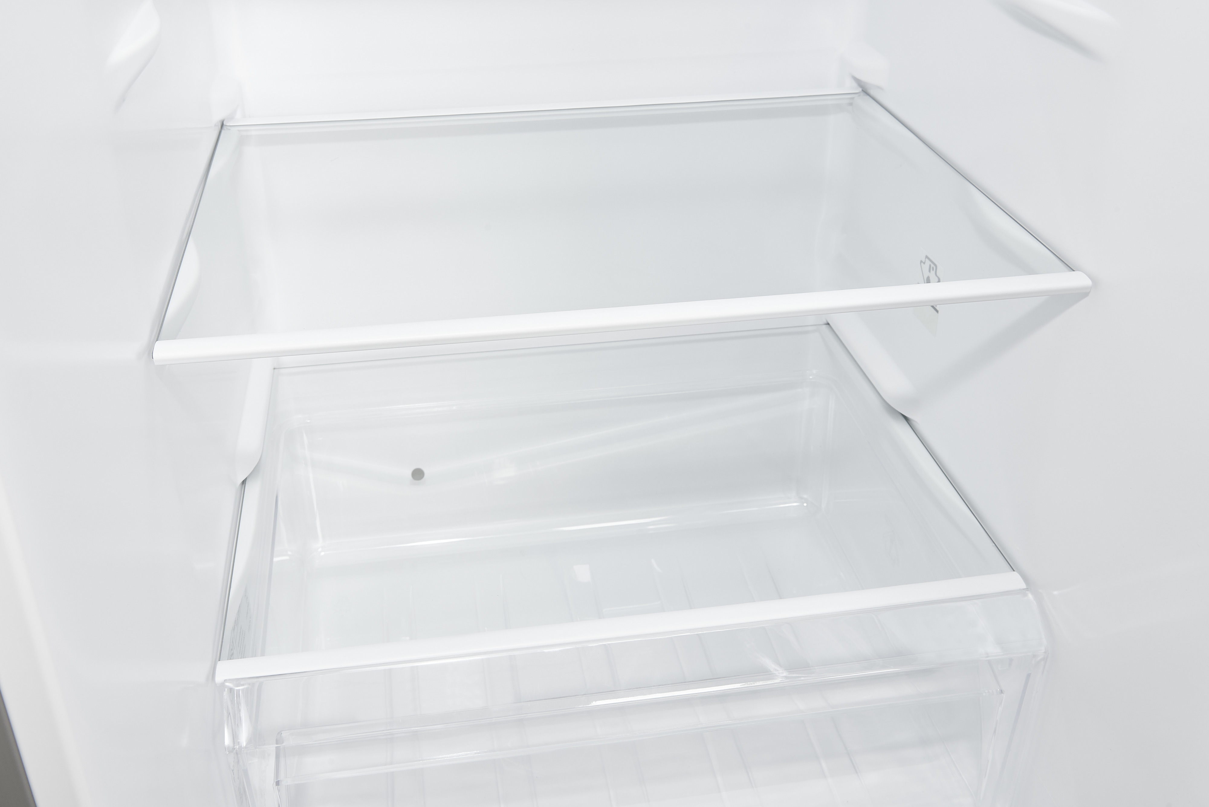 Im Kühlschrank: Klare Glasböden und eine transparente Schublade sind zu sehen, vor weißem Hintergrund.
