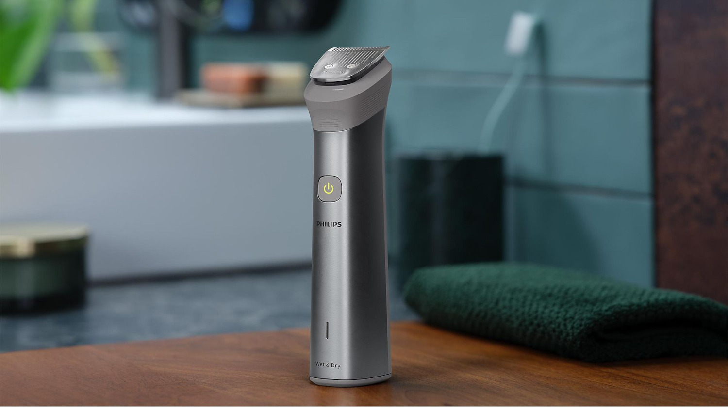 Une tondeuse Philips sur une surface en bois. Une serviette verte et un récipient en arrière-plan.