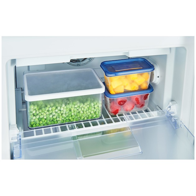 Interior de refrigerador con recipientes. Guisantes, mango, fresas. Contenedores claros y azules.