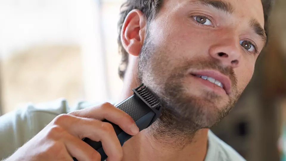 Man shaving his beard with a trimmer. Close-up shot.