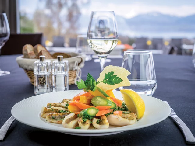 Piatto di cibo con pesce, verdure e limone in un ambiente ristorante.