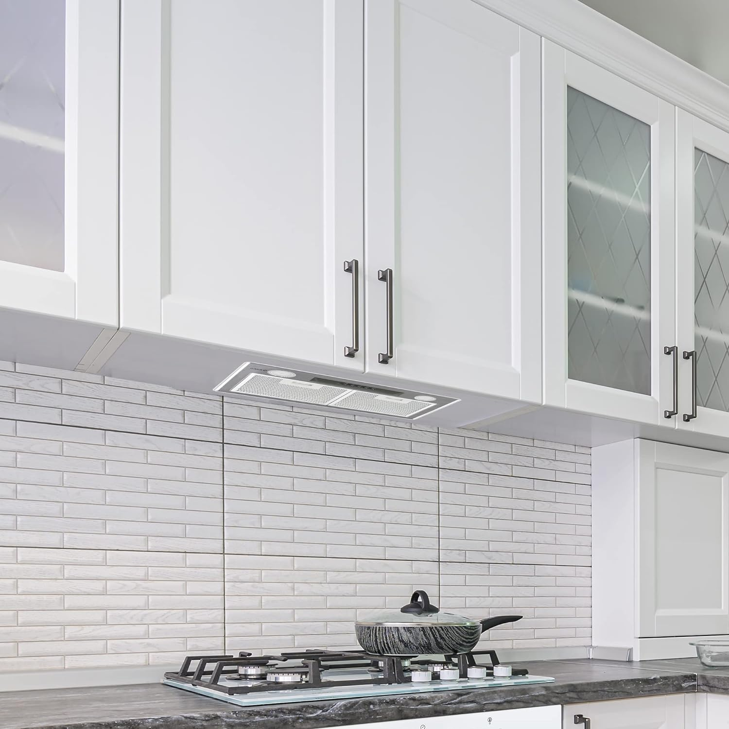 Cocina blanca moderna con gabinetes blancos, salpicadero de ladrillo y estufa.