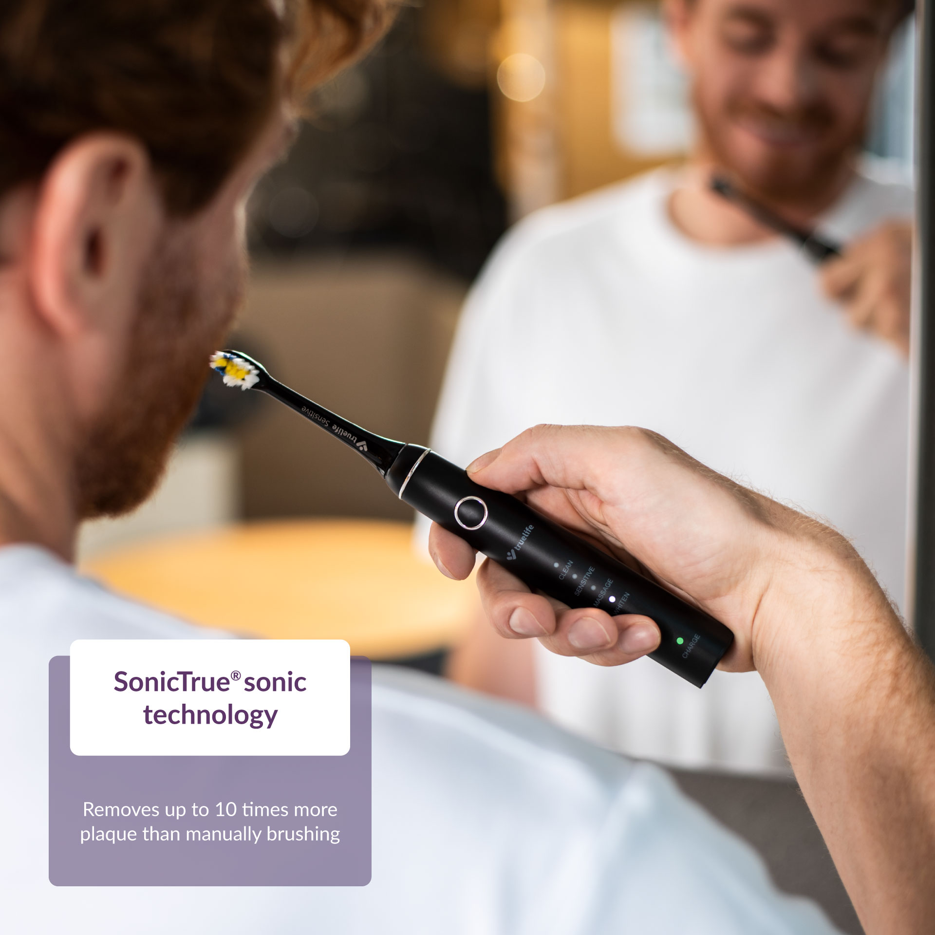 Férfi fekete elektromos fogkefével tisztítja a fogát, 'SonicTrue' hangtechnológiával, lepedéket eltávolítva.