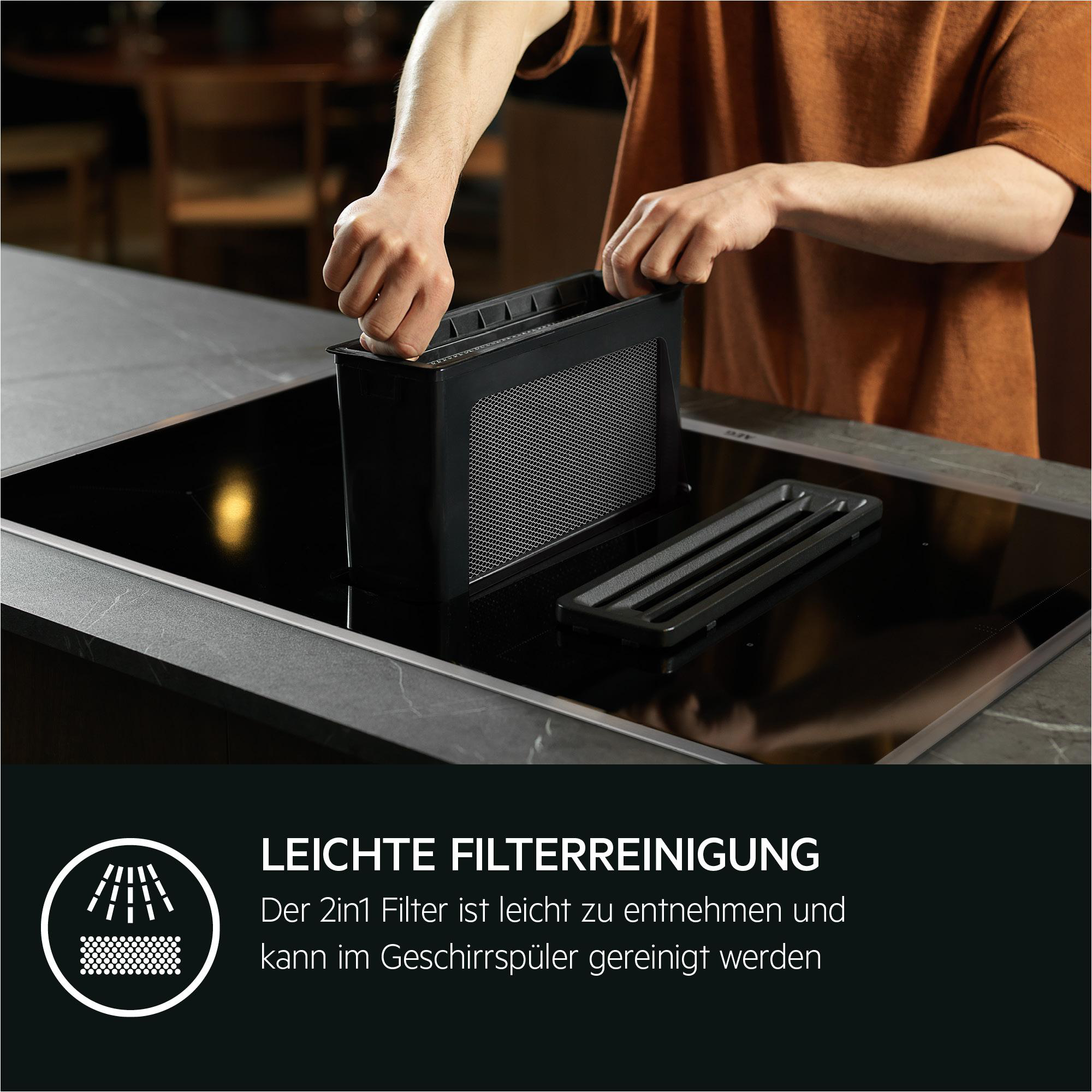Person entfernt Filter von einem schwarzen Kochfeld. Text: Leichte Filterreinigung.