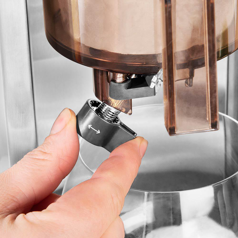 Hand dreht einen silbernen Knopf an einer Maschine, Nahaufnahme.