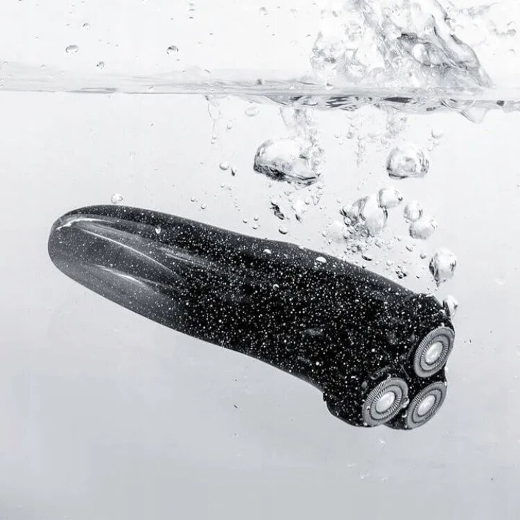 Golarka elektryczna zanurzona w wodzie z bąbelkami wokół niej.