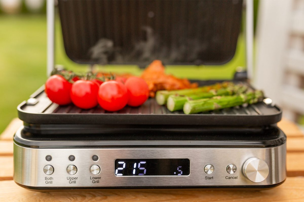 Grill z pomidorami, szparagami i piekącym się mięsem.