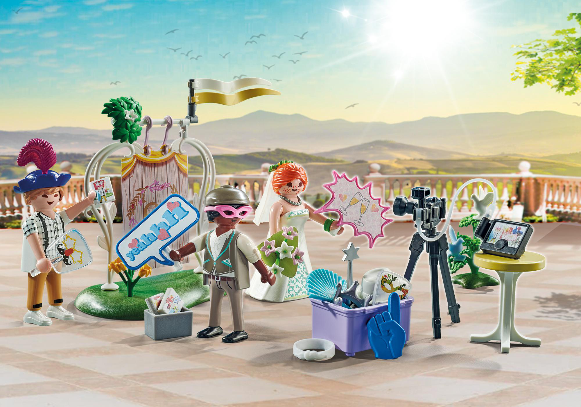 Playmobil-Hochzeitsszene. Braut, Bräutigam und Gäste mit Dekorationen und sonnigem Himmel.