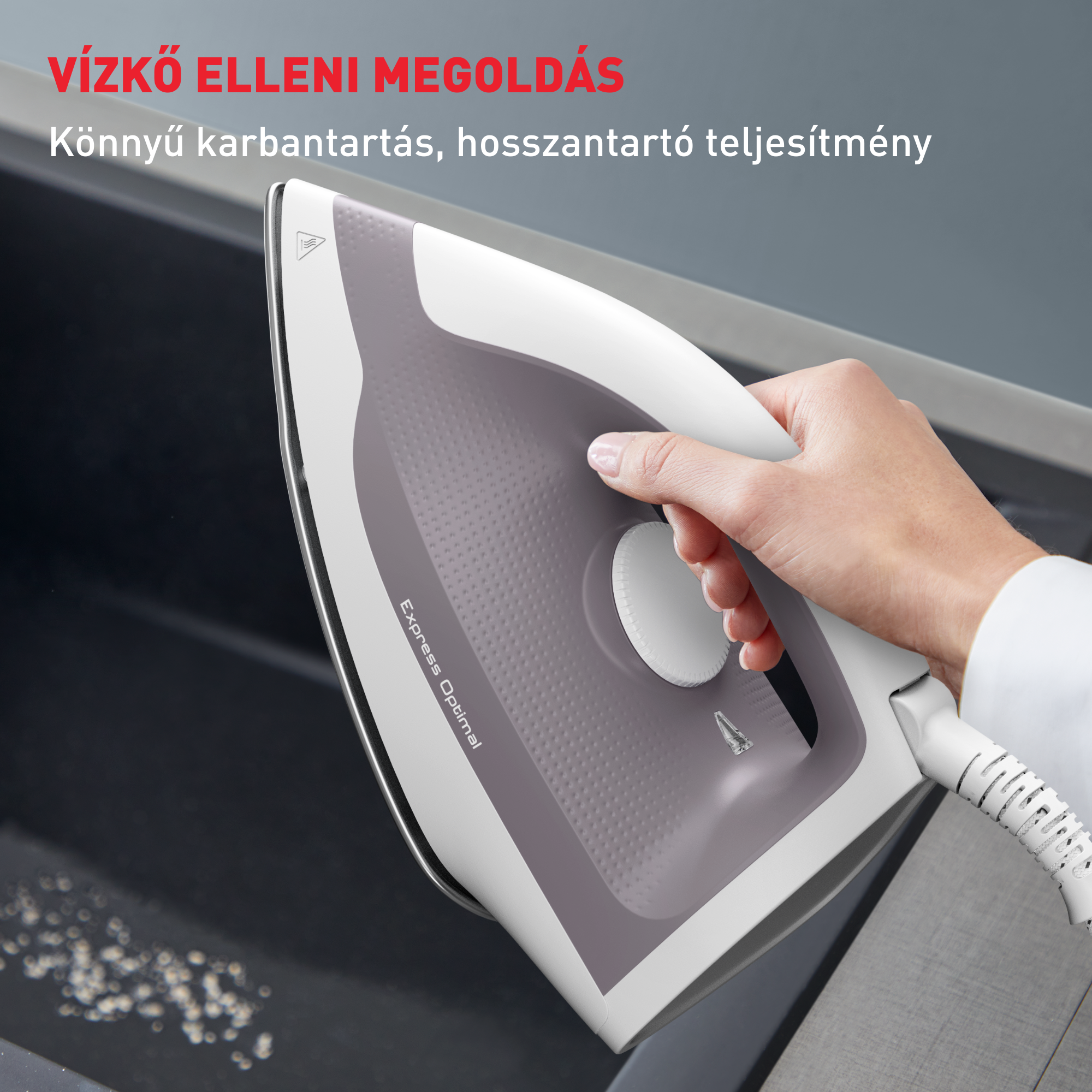 Egy kéz egy fehér-szürke vasalót tart, mutatva a vasaló felületét és fogantyúját, szöveggel.
