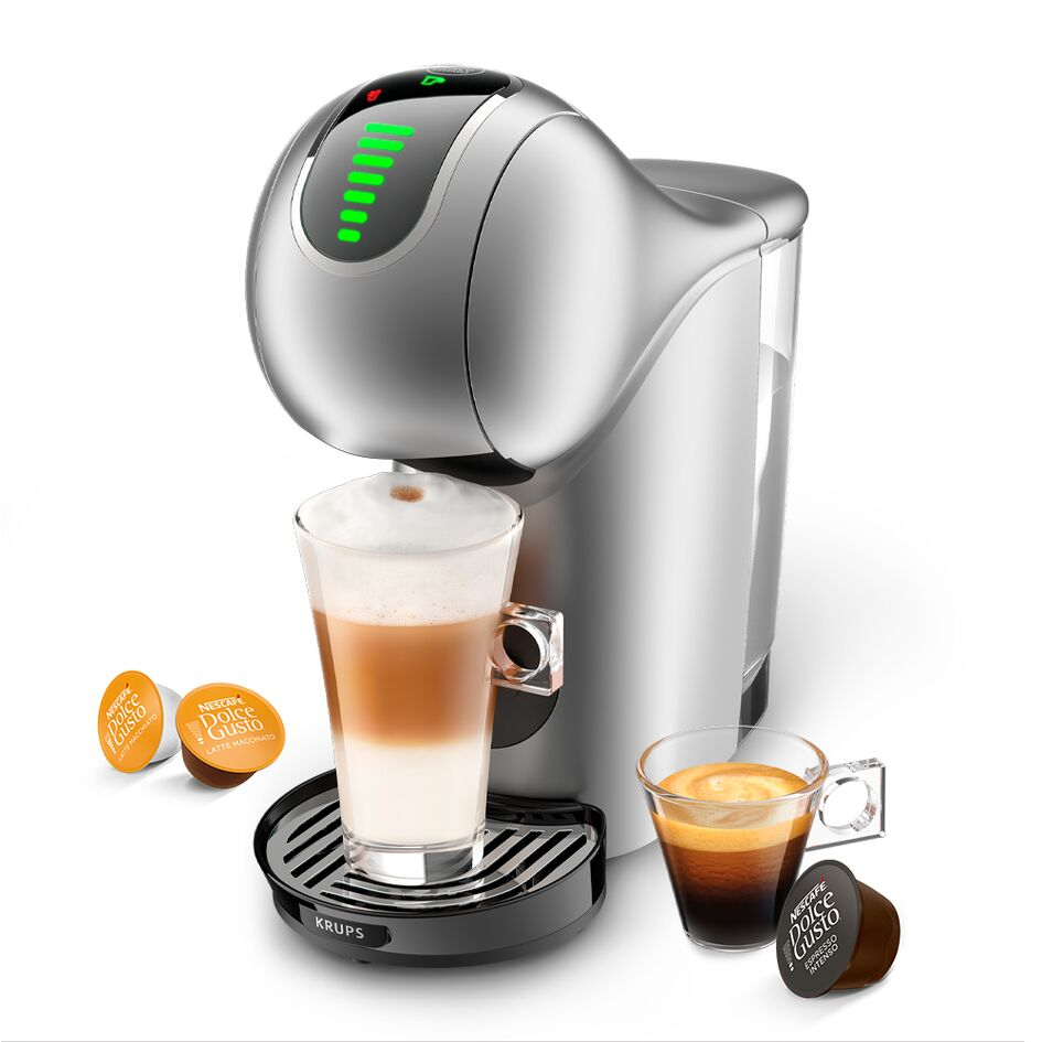 Kávéfőző: Ezüst design, egy pohár latte-val és eszpresszóval, valamint közeli kávépárnákkal.