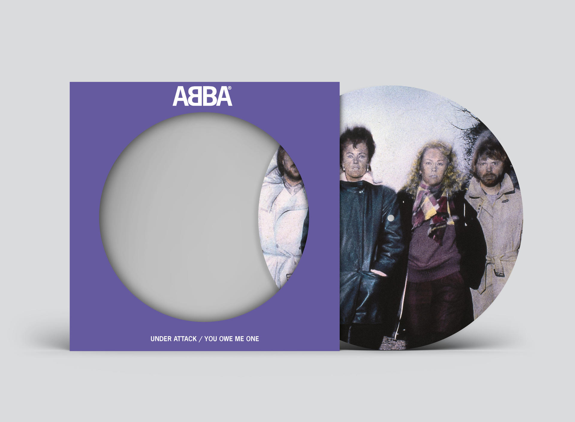 Albumcover von ABBA. Bandmitglieder stehen draußen. Der Albumtitel ist "Under Attack / You Owe Me One".