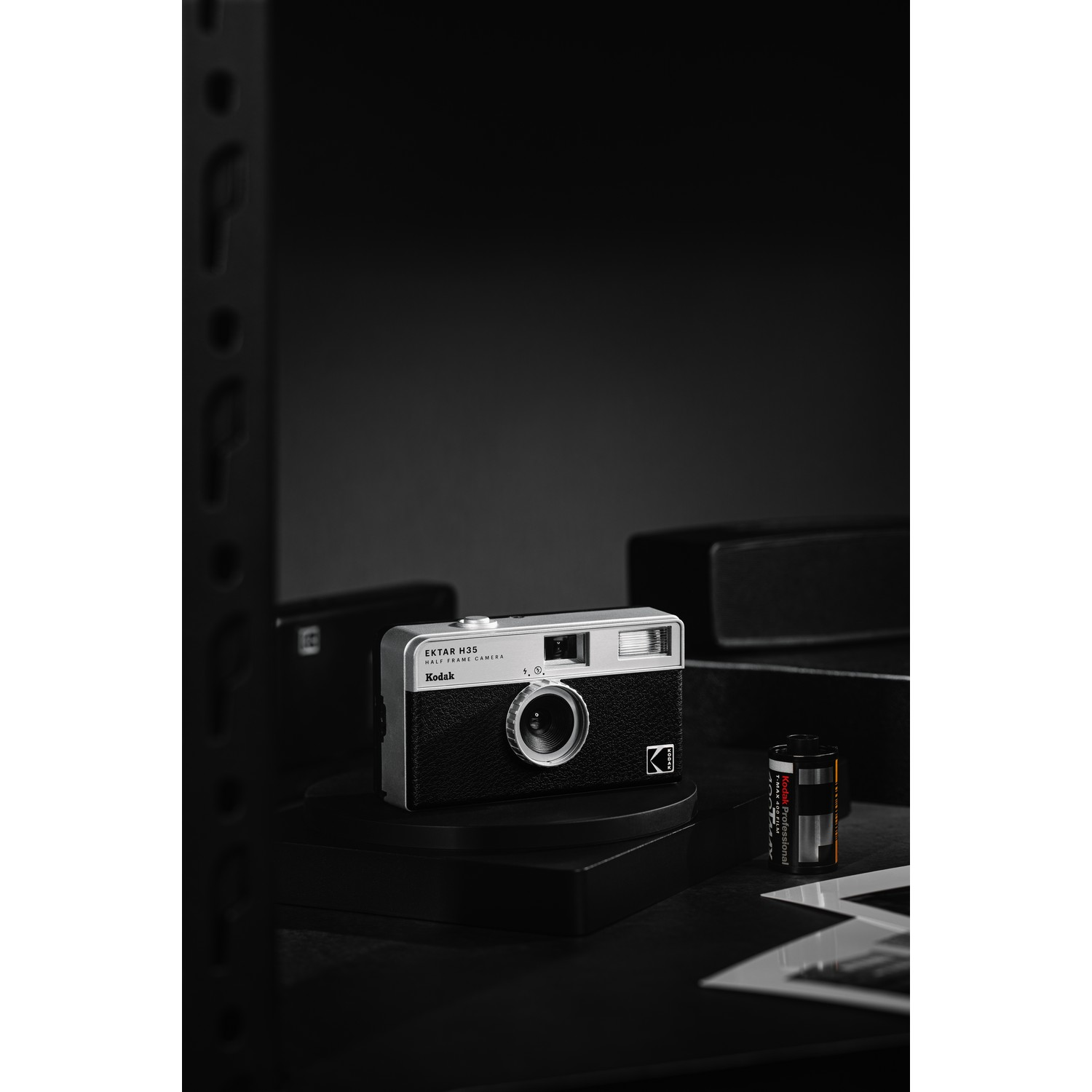 A Kodak Ektar H35 camera on a black stand with film and other items.