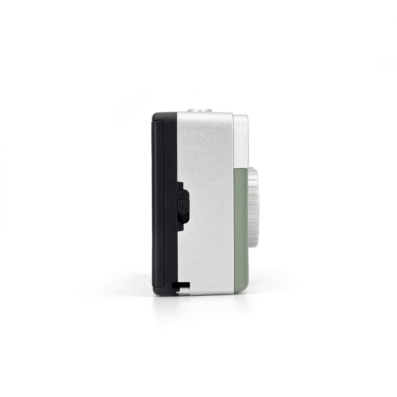 Small, silver, black, and green camera. It is on a white surface. The side of the camera is visible.