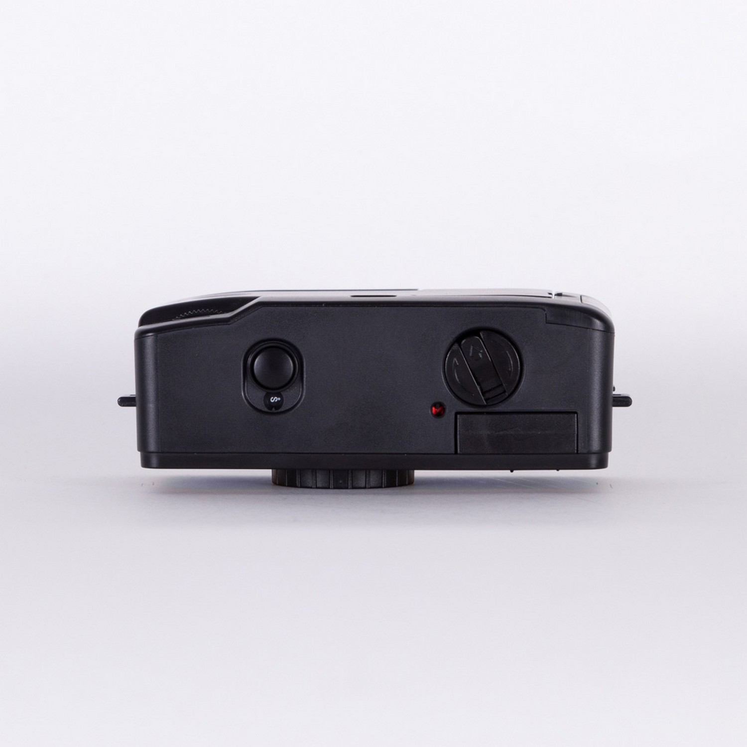 A black camera, top view, with two circular buttons and a dial, on a white surface.