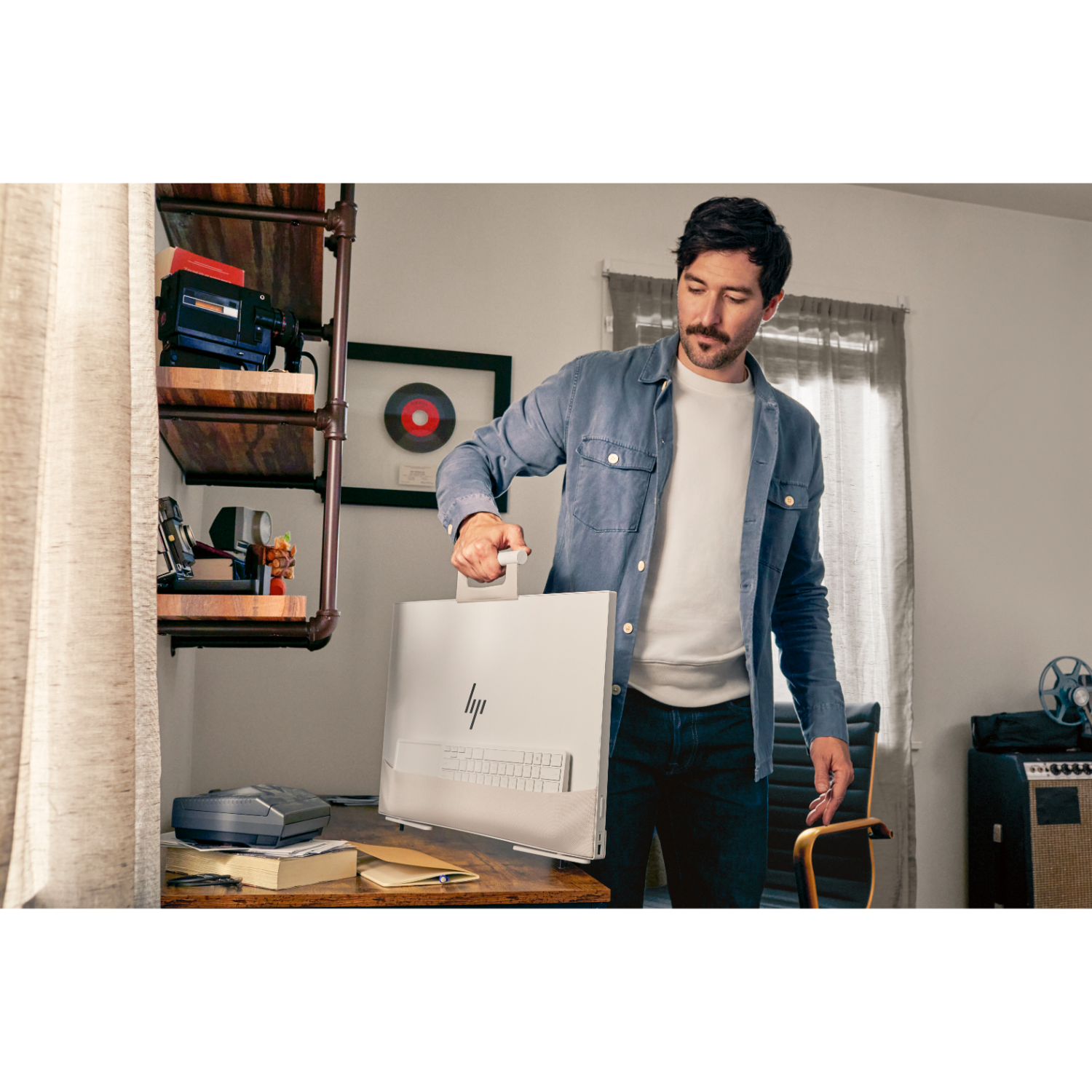 Man houdt een grote computermonitor vast. De monitor is wit met een toetsenbord. Achtergrond is een kamer.